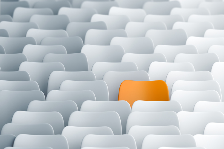 stock image of orange chair in sea of white chairs