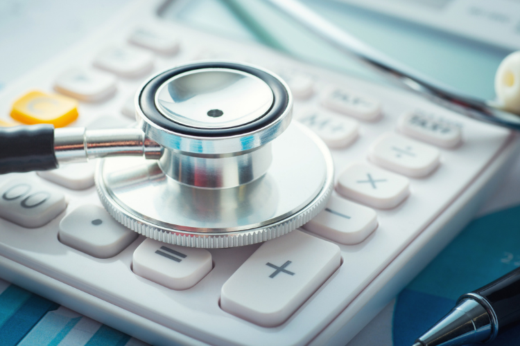 A close-up view of a stethoscope resting on a white calculator.