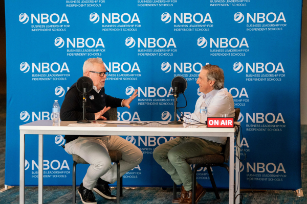 Jeff Shields, left, speaks with Frank Aloise, right, in front of a blue and white NBOA branded banner