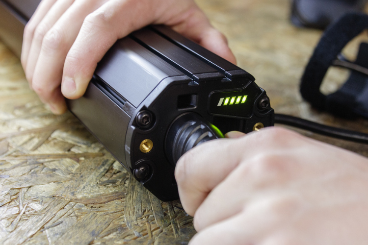 Hands plugging in charger to an electric bicycle battery.