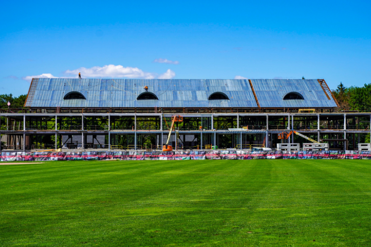 Construction site with a skeletal steel frame building against a blue sky.