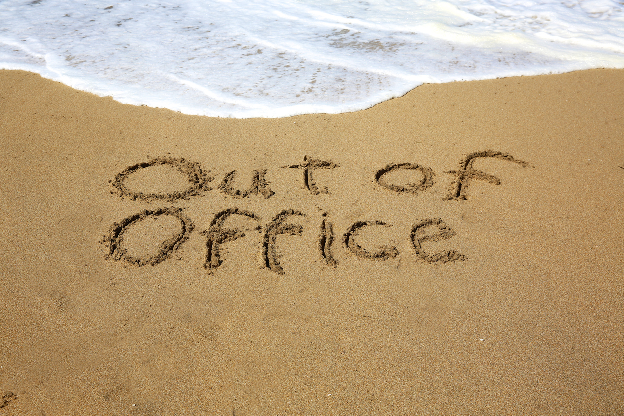 beach with out of office written in sand